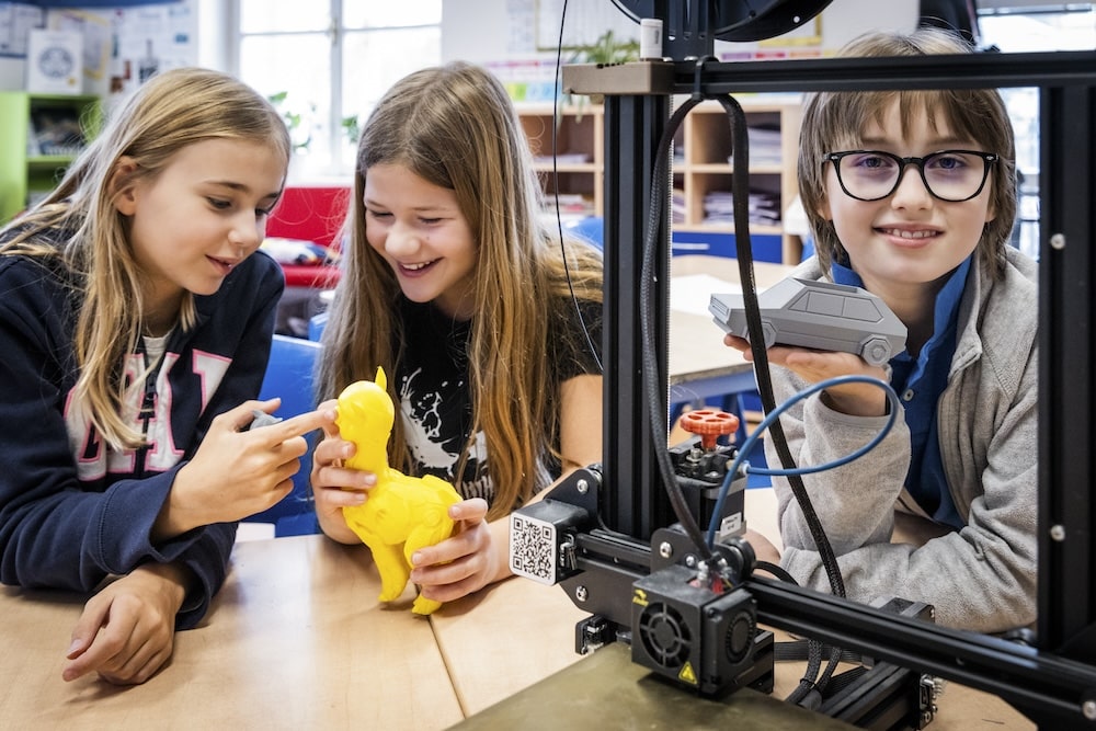 Primary students work with 3D printer.